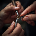 Close-up of hands working on a small metal object with tools against a dark background