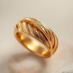 Gold ring with a textured design on a soft beige background