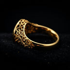 Gold ring with intricate design on a black background