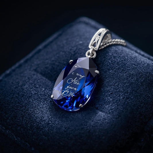 Blue teardrop pendant with engraved text on a dark background