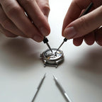 Person repairing a watch with tools on a white background